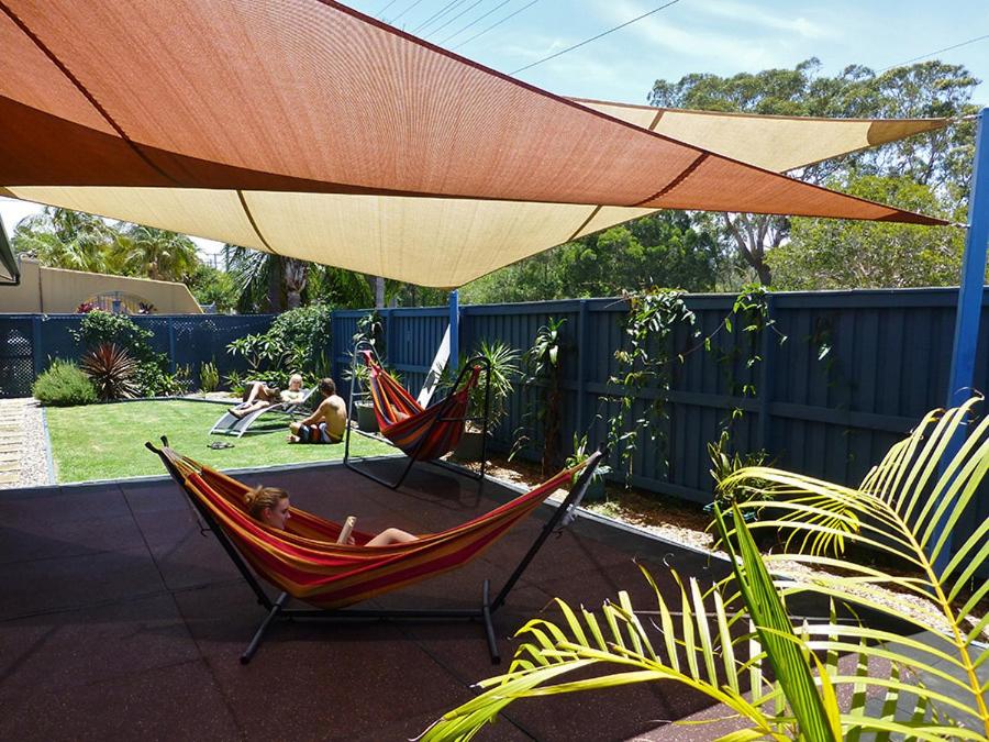 a woman sitting in a hammock under an umbrella at Aussitel Backpackers in Coffs Harbour