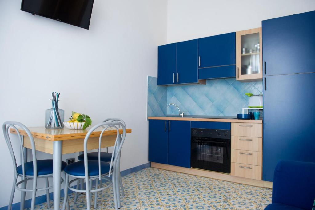 a kitchen with blue cabinets and a table and chairs at Residence Panoramic in Maiori