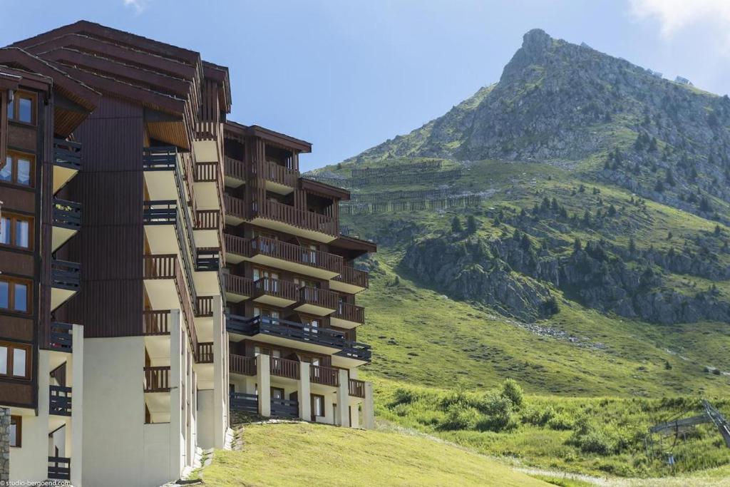 ein Gebäude auf einem Hügel mit einem Berg im Hintergrund in der Unterkunft Résidence Les Gémeaux - Belle Plagne in La Plagne