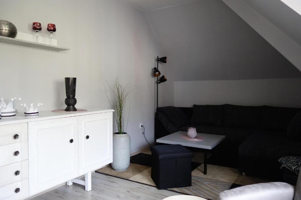 a living room with a black couch and a table at Ferienwohnung Waldstuben in Goldenstedt