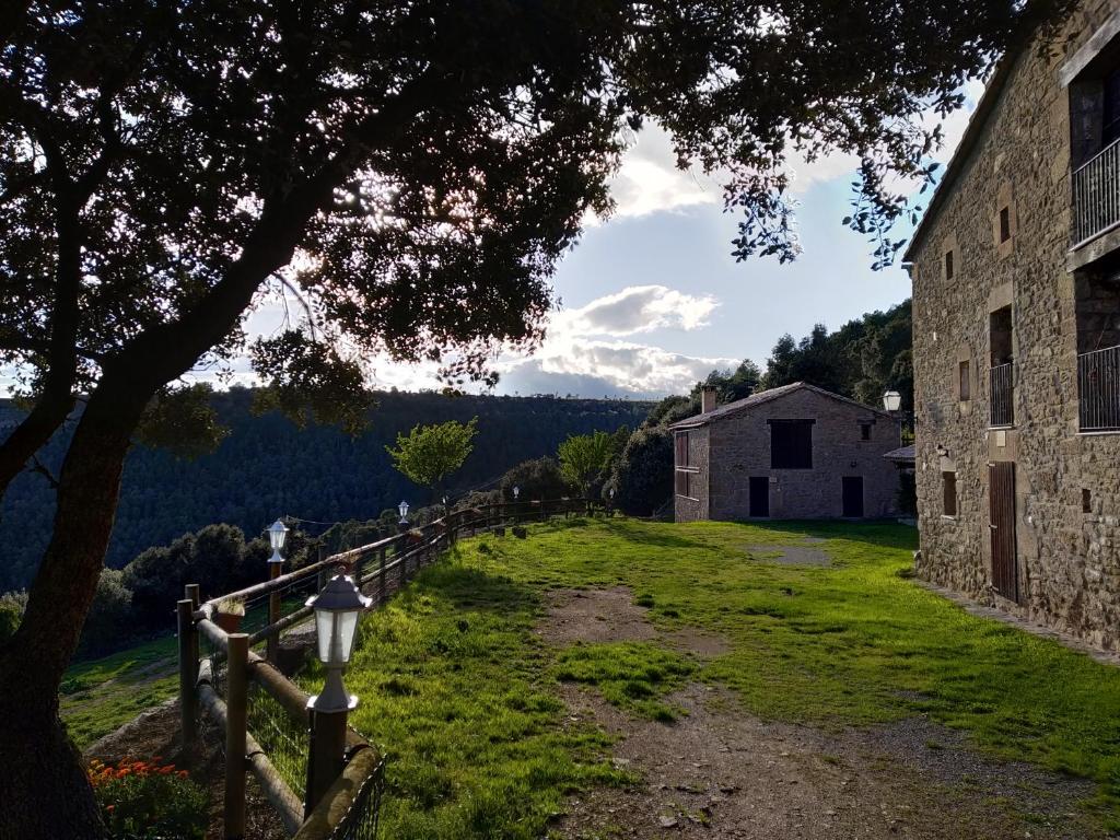 um caminho que leva a um edifício com uma árvore em Les Cases De Borrells em Lladurs