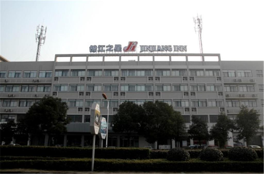 Un grand bâtiment blanc avec un panneau en haut dans l'établissement Jinjiang Inn - Economic Development Wujiang, à Suzhou