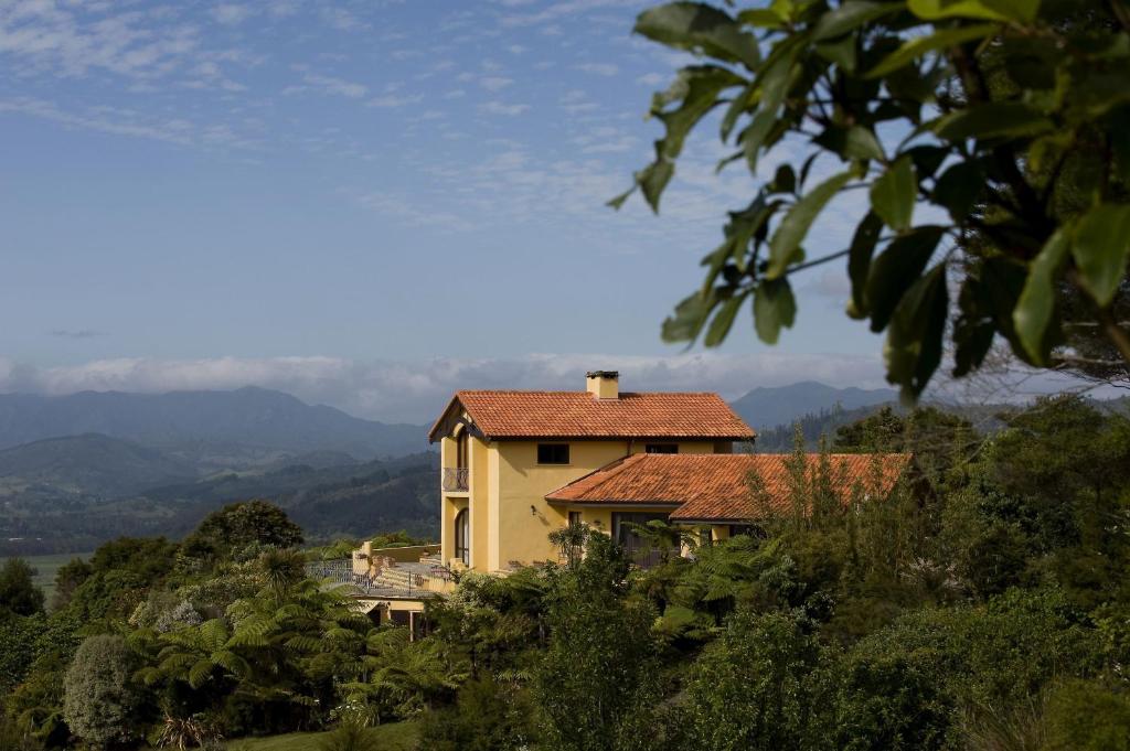 a house on a hill with mountains in the background at Villa Toscana in Whitianga