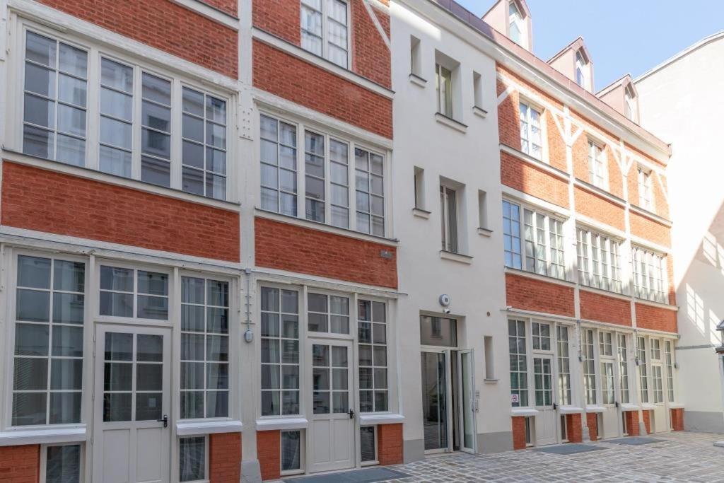 a large brick building with windows on a street at Lofts Philippe-Auguste in Paris