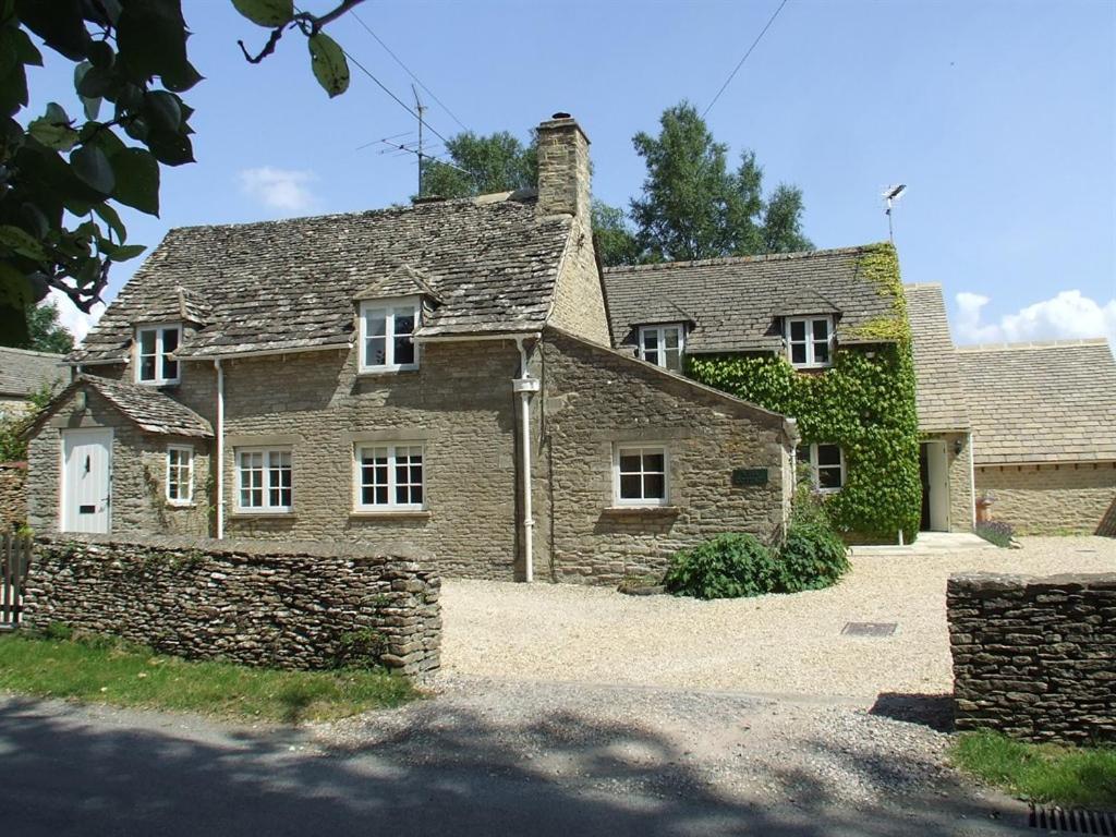 uma velha casa de pedra com hera a crescer nela em Well Cottage B and B em Cirencester