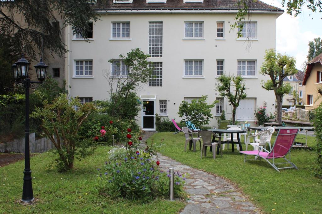 un jardin avec une table et des chaises et un bâtiment dans l'établissement Hotel de L'Europe, La Roche-Posay, à La Roche-Posay