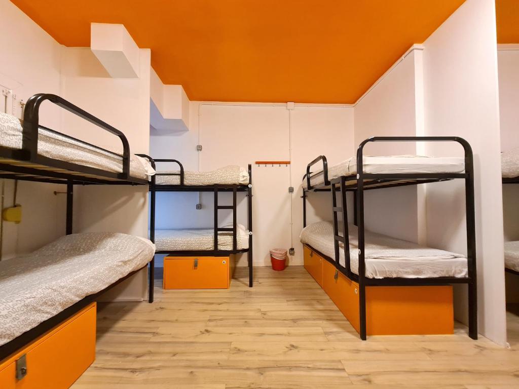 巴塞隆納的住宿－Arc House Gracia，客房设有三张双层床和橙色天花板。