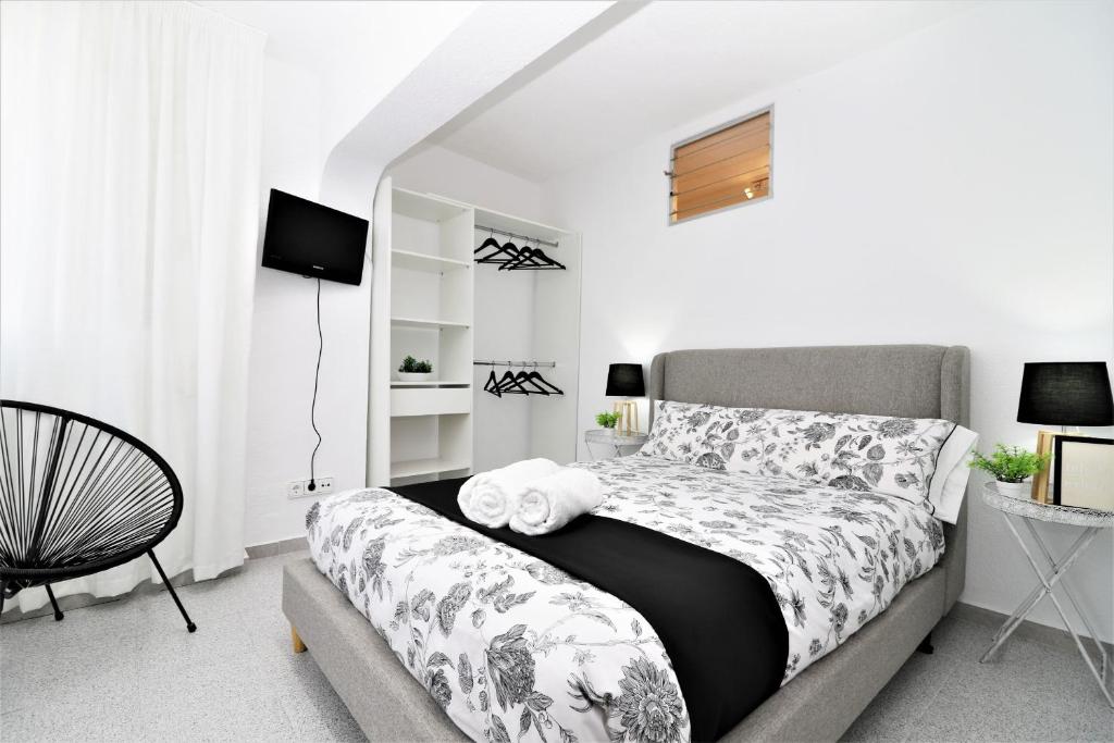 a white bedroom with a bed and a chair at Alameda Beach Centro in Benidorm