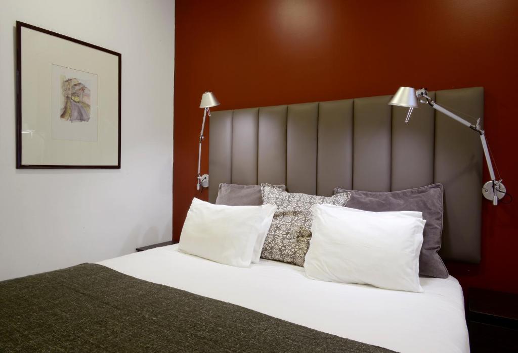 Un dormitorio con una cama con sábanas y almohadas blancas. en Flats Castelo - HOrigem, en Lisboa