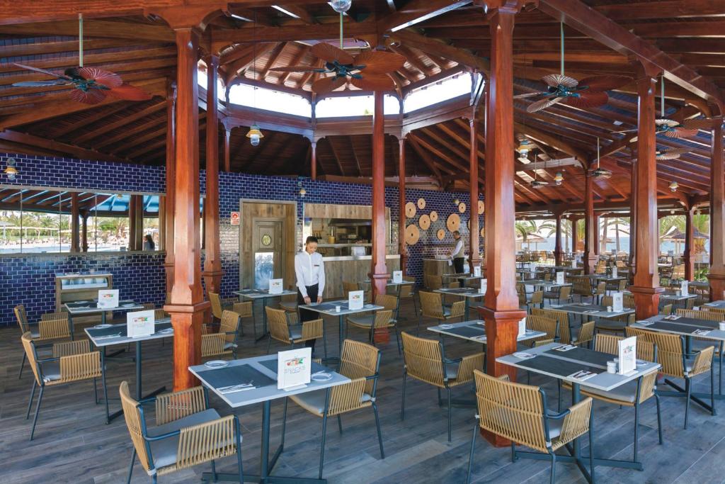un restaurante con mesas y sillas y un hombre de pie en el fondo en Hotel Riu Palace Tenerife, en Adeje