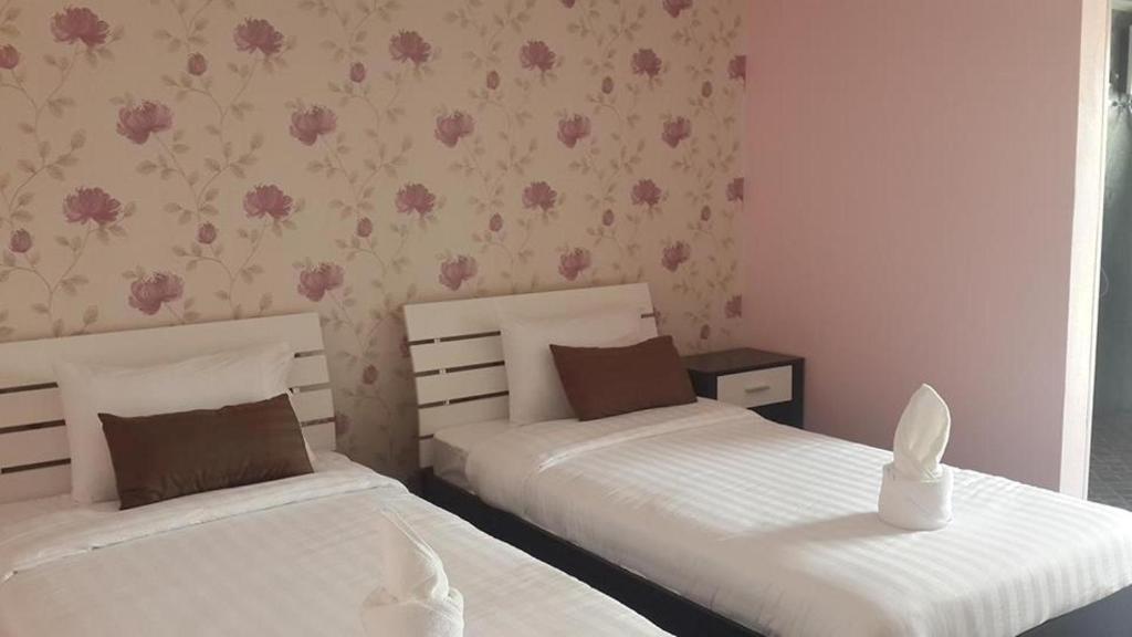 2 camas en un dormitorio con flores rosas en la pared en Nalin Place, en Ranong