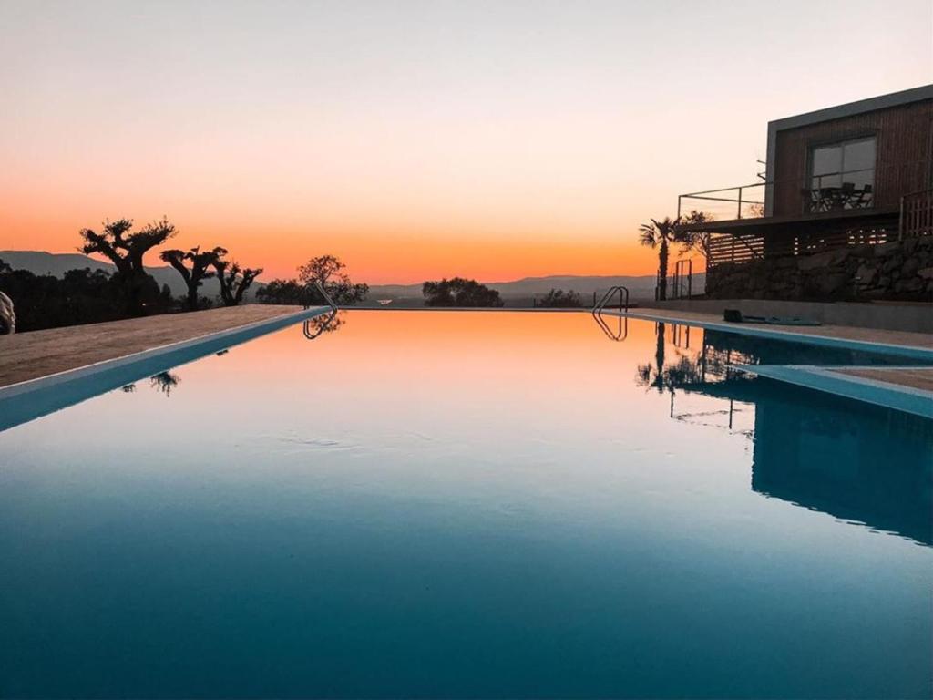 einen Pool mit Sonnenuntergang im Hintergrund in der Unterkunft MyStay - Bungalows in Quinta dos Sobrais in Valença