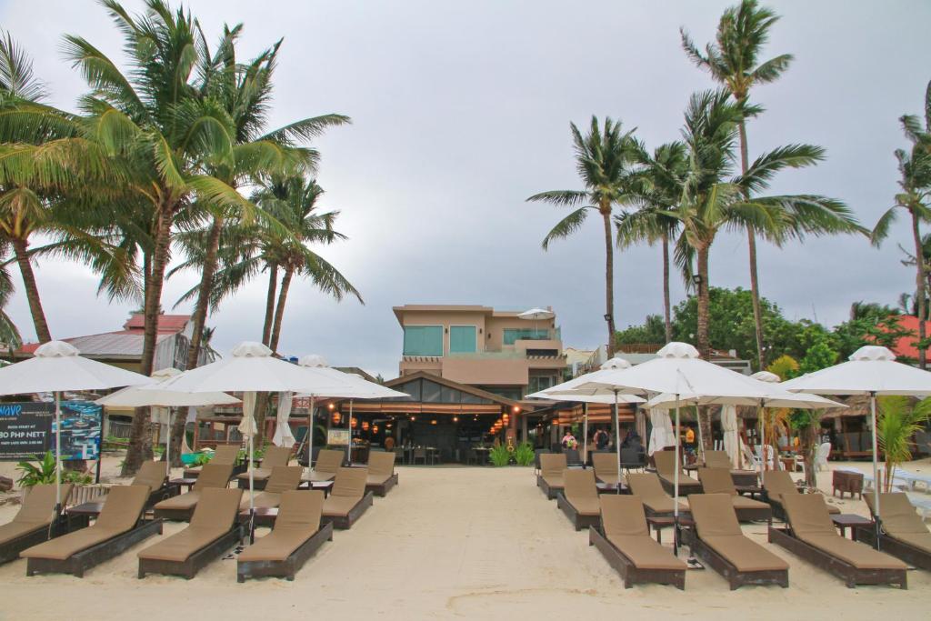 einen Strand mit Liegestühlen, Sonnenschirmen und Palmen in der Unterkunft Two Seasons Boracay Resort in Boracay