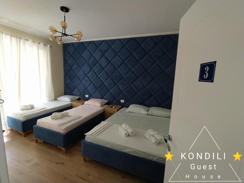 1 dormitorio con 2 camas y pared azul en Guest House Kondili, en Përmet