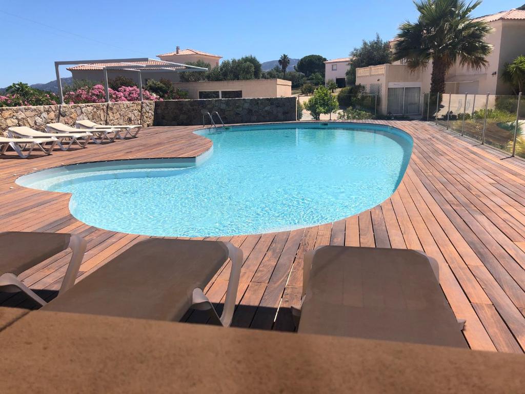 a swimming pool with chairs and a wooden deck at Manureva Calvi in Calvi