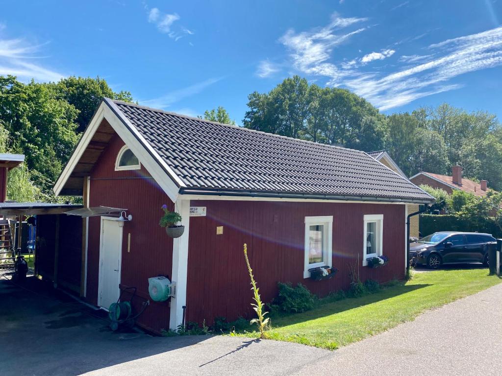a red house with a garage and a car at Liverpoolsstugan in Motala