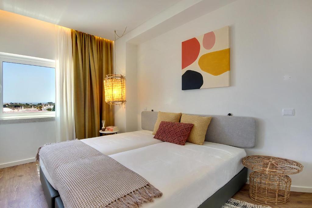a white bedroom with a bed and a window at Apartamento Boavista - Sea View in Albufeira