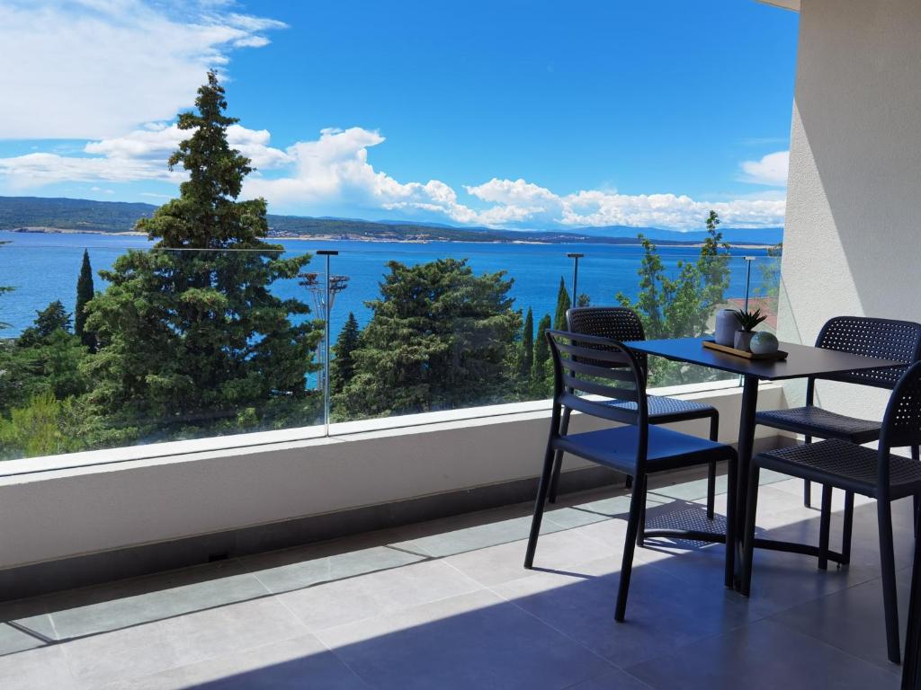 balcón con mesa, sillas y vistas al agua en Apartments Jadranka, en Selce