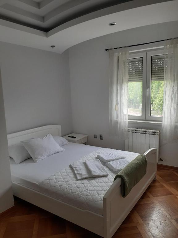 a white bedroom with a white bed and a window at Loznicki stan na dan 2 - stan na dan Loznica in Loznica
