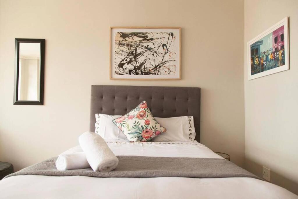 a bedroom with a bed with white sheets and pillows at Four Seasons Apartments in Cape Town