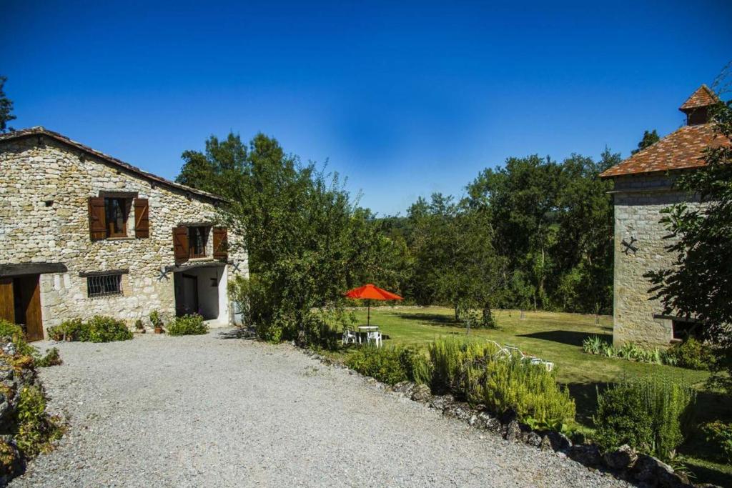 a stone building with a table and an orange umbrella at CHEZ SIMONE in Senouillac