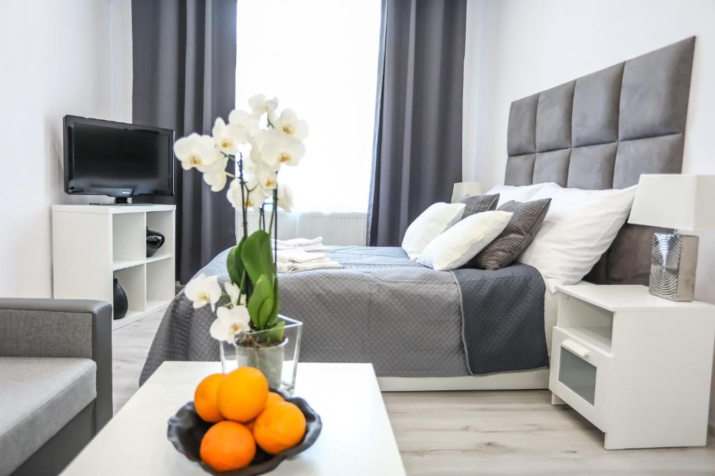a living room with a bed and a table with oranges on it at Cracow by Night Apartments in Krakow