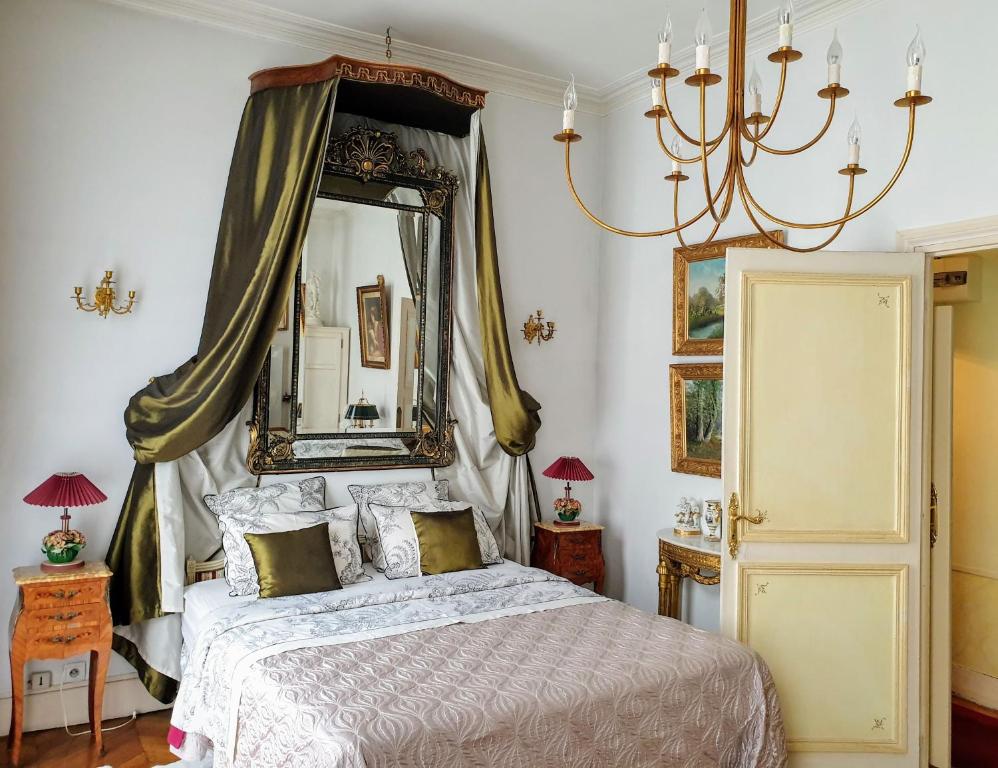 a bedroom with a bed with a mirror and a chandelier at Royal Hubert in Provins