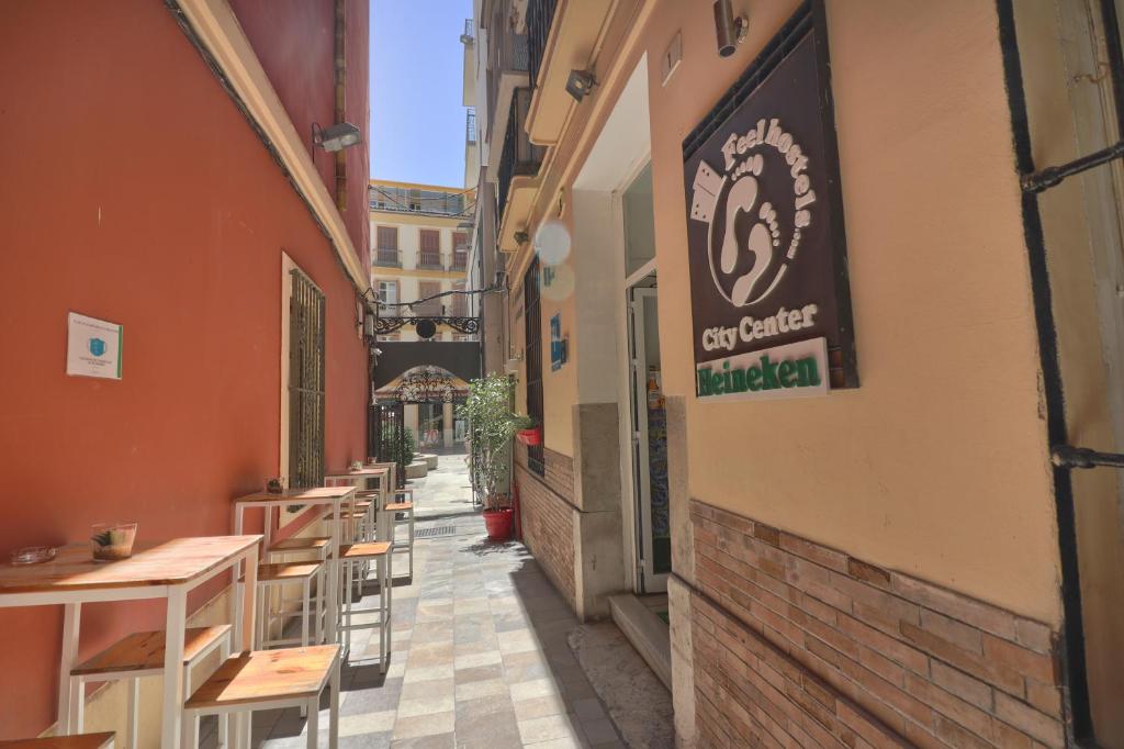 eine schmale Gasse mit Tischen und Stühlen auf einem Gebäude in der Unterkunft Feel Hostels City Center in Málaga