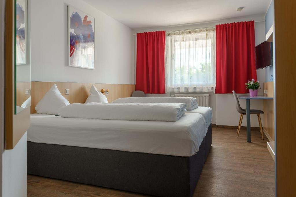 two beds in a hotel room with red curtains at Motel Drei König- Ihr Transithotel in Heimsheim