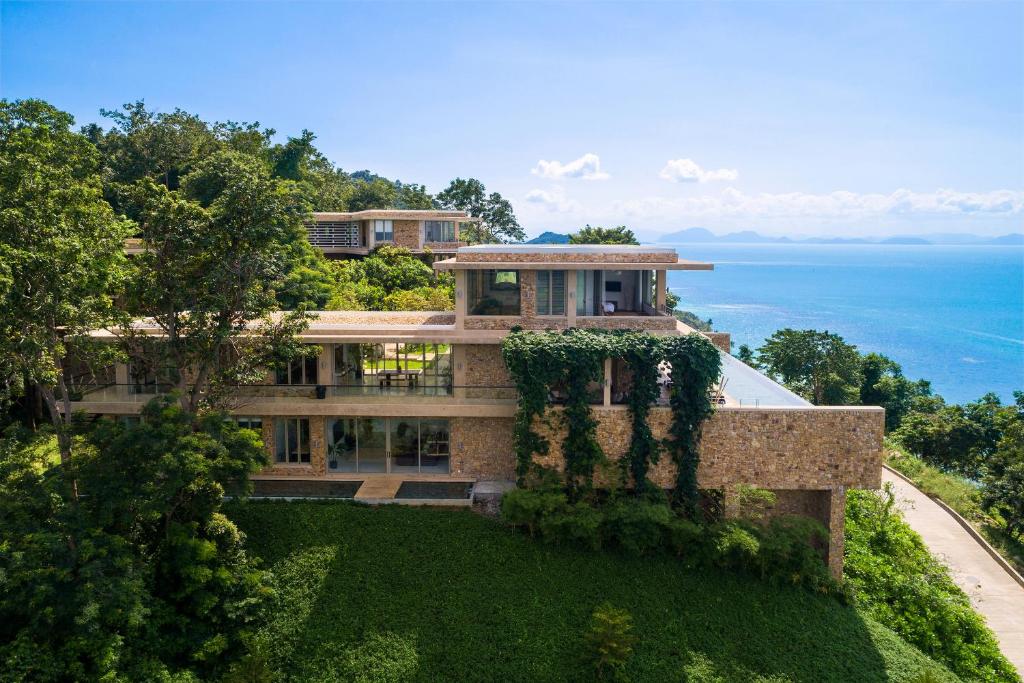 een huis op een heuvel met de oceaan op de achtergrond bij Baan Sang at Five Islands Estate - Private Luxury Retreat in Taling Ngam Beach