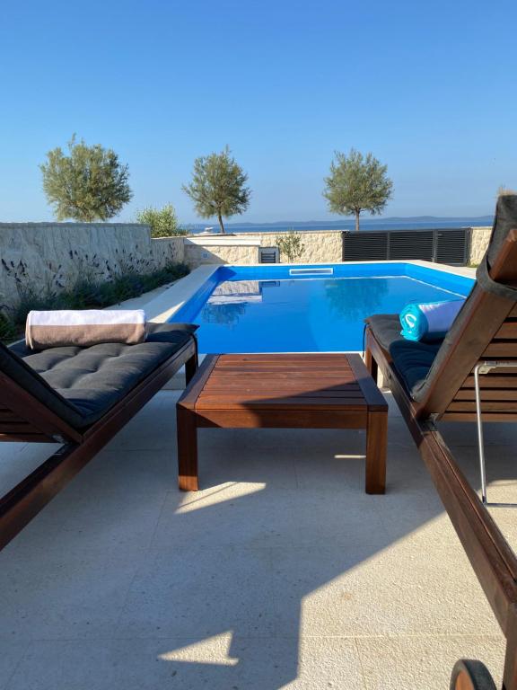 a patio with two chairs and a table next to a swimming pool at Holiday House Laura in Vir