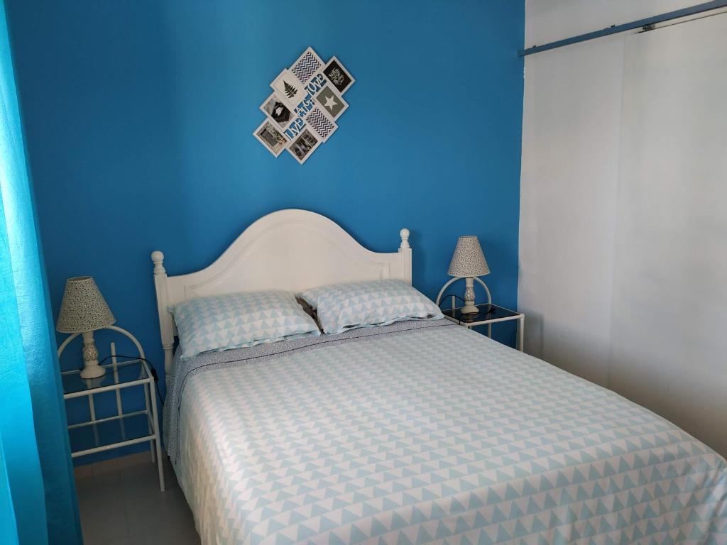 a blue bedroom with a white bed and two lamps at Vivenda Familia Pedro in Vila do Bispo
