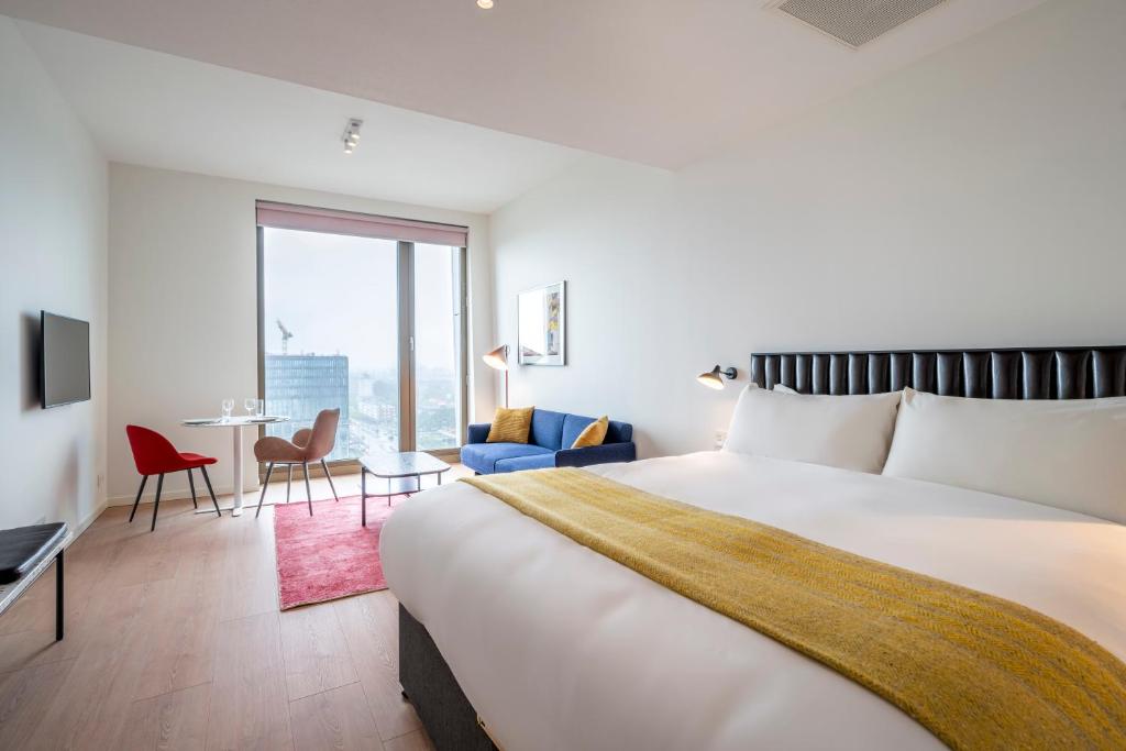 ein Hotelzimmer mit einem großen Bett und einem Tisch in der Unterkunft PREMIER SUITES PLUS Amsterdam in Amsterdam