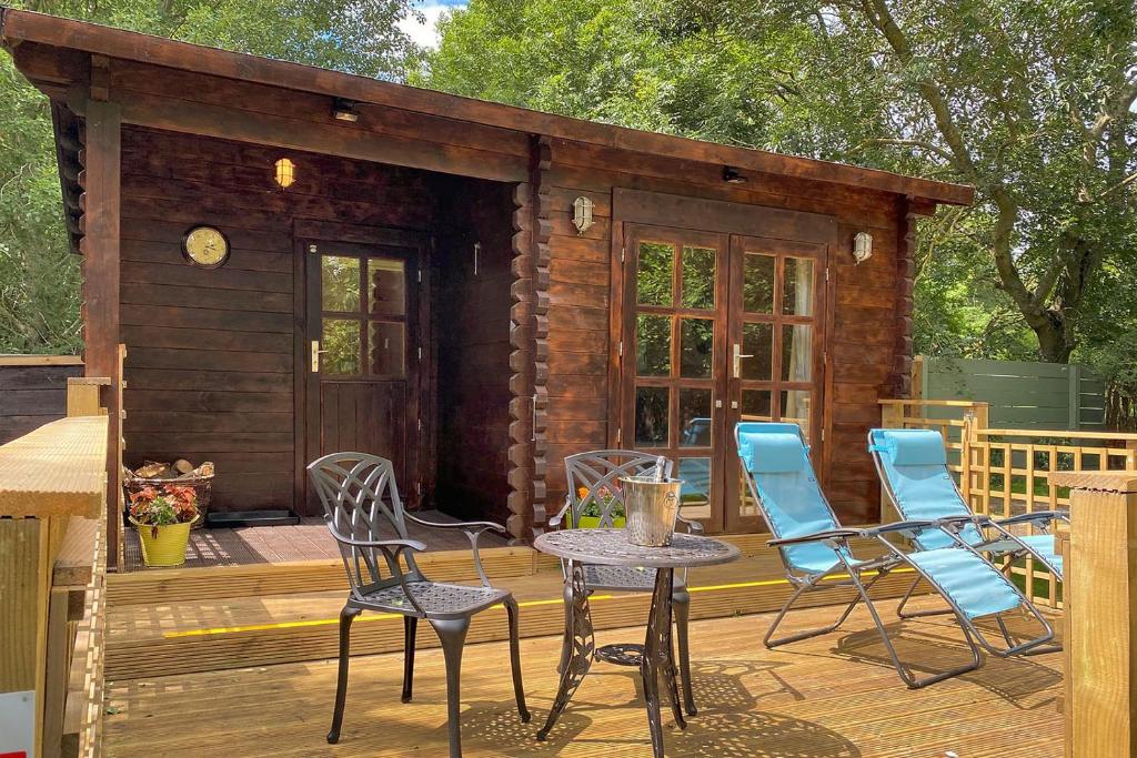 a cabin with chairs and a table on a deck at The Lodge with hot tub in Maidstone