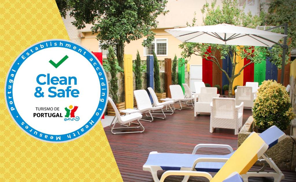 un cartello per un patio pulito e sicuro con sedie e ombrellone di By Doors Hostel a Porto