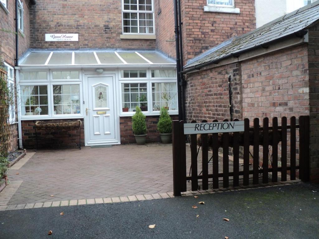 a sign in front of a brick building at Grove House Guest House in Telford