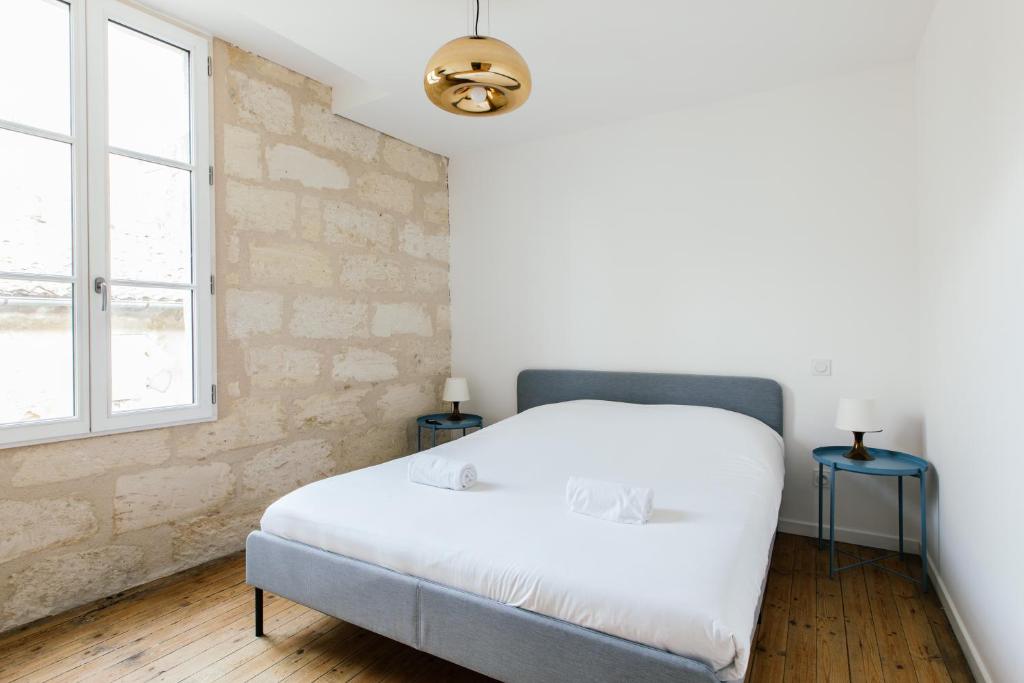 een slaapkamer met een wit bed en een raam bij Appartement spacieux et lumineux avec climatisation Halle 1ER in Castillon-la-Bataille