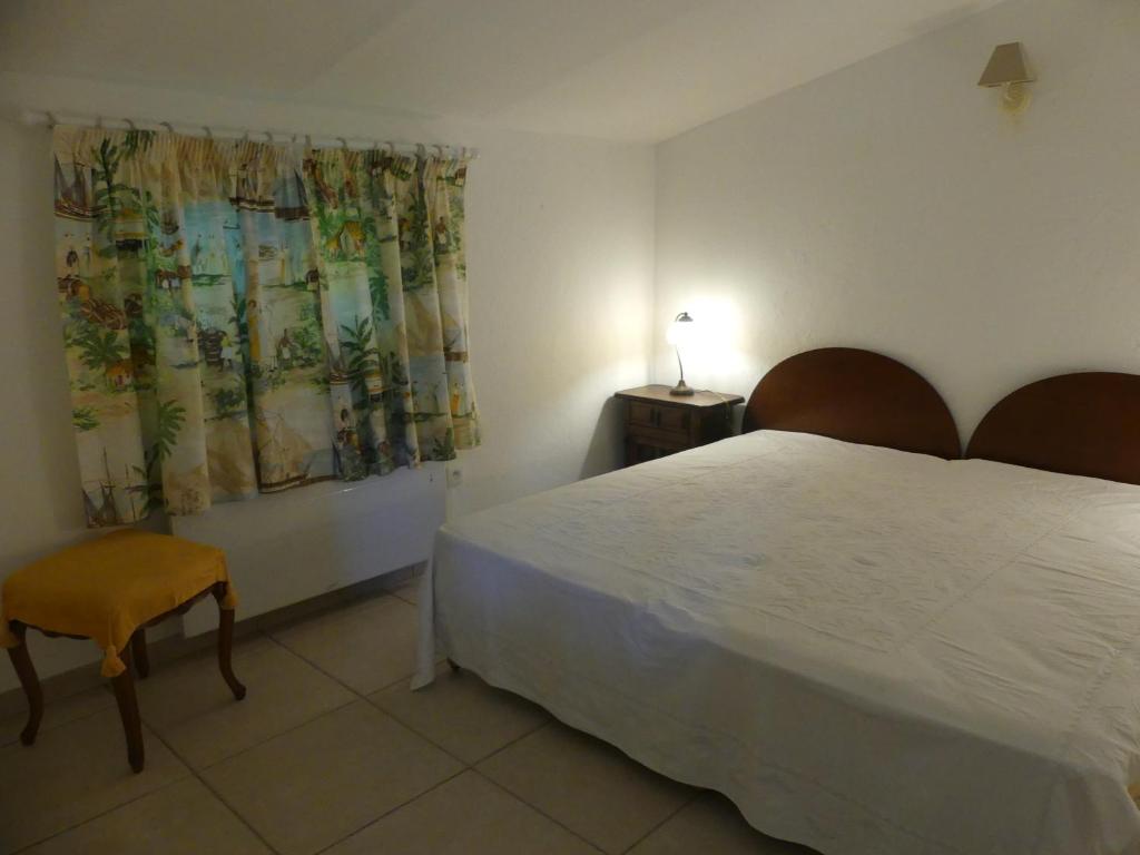 een slaapkamer met een wit bed en een stoel bij Maisonnette au calme et proche mer in Mandelieu-la-Napoule