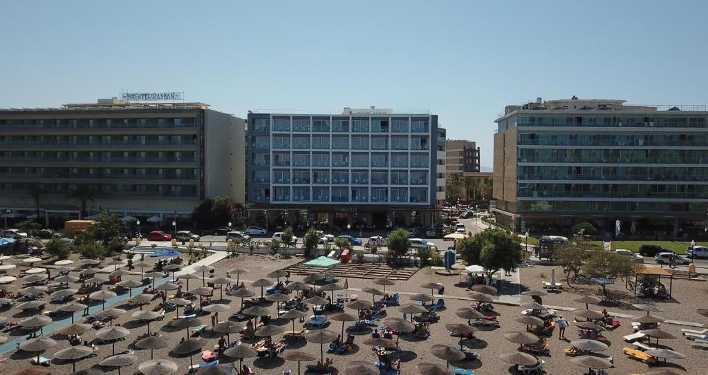 un gran aparcamiento con sombrillas frente a los edificios en Ibiscus Hotel, en Rodas