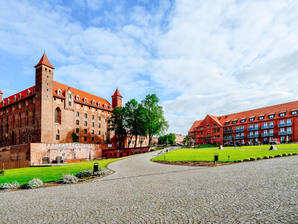 um grande edifício de tijolos com um relvado verde em frente em Hotel Zamek Gniew em Gniew