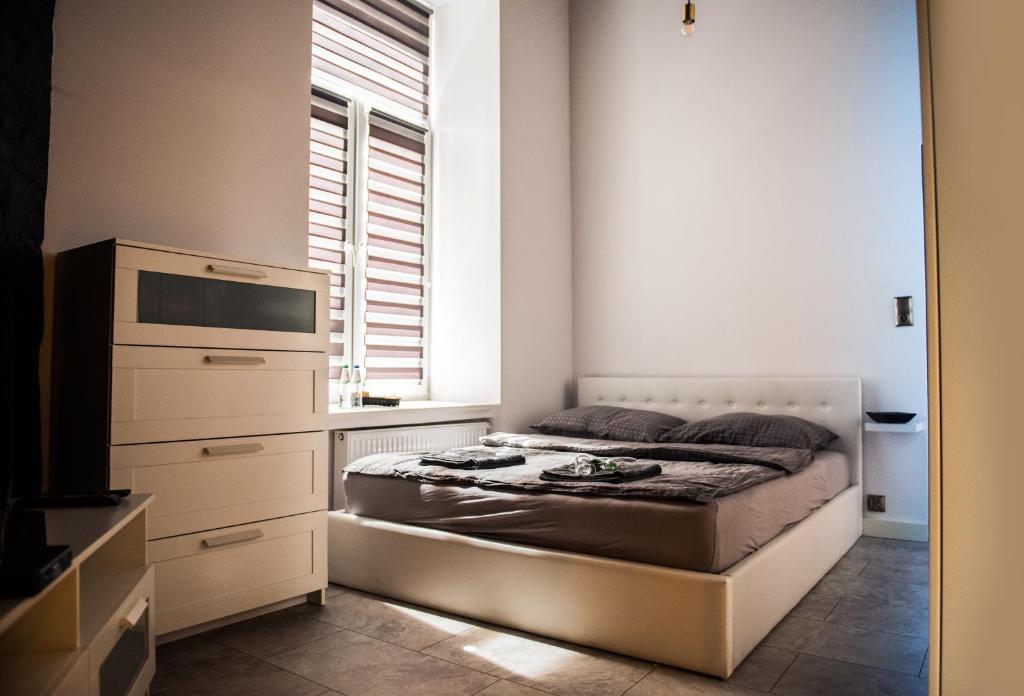a bedroom with a bed and a dresser and a window at DarkHouse in Łódź