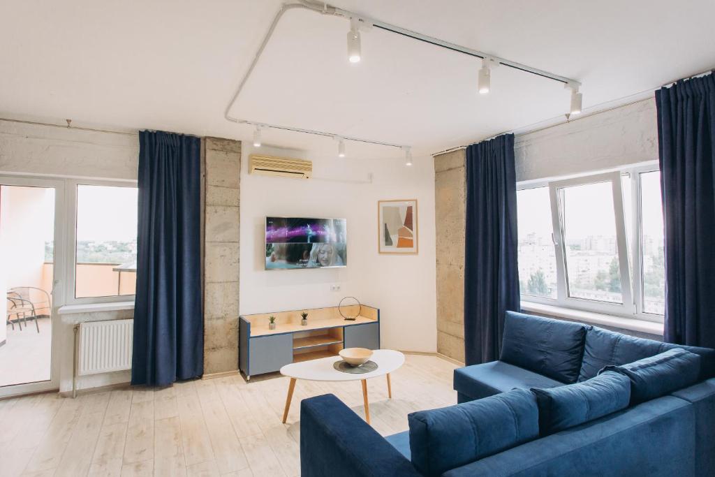 uma sala de estar com um sofá azul e uma mesa em loft Apartmen em Sumy
