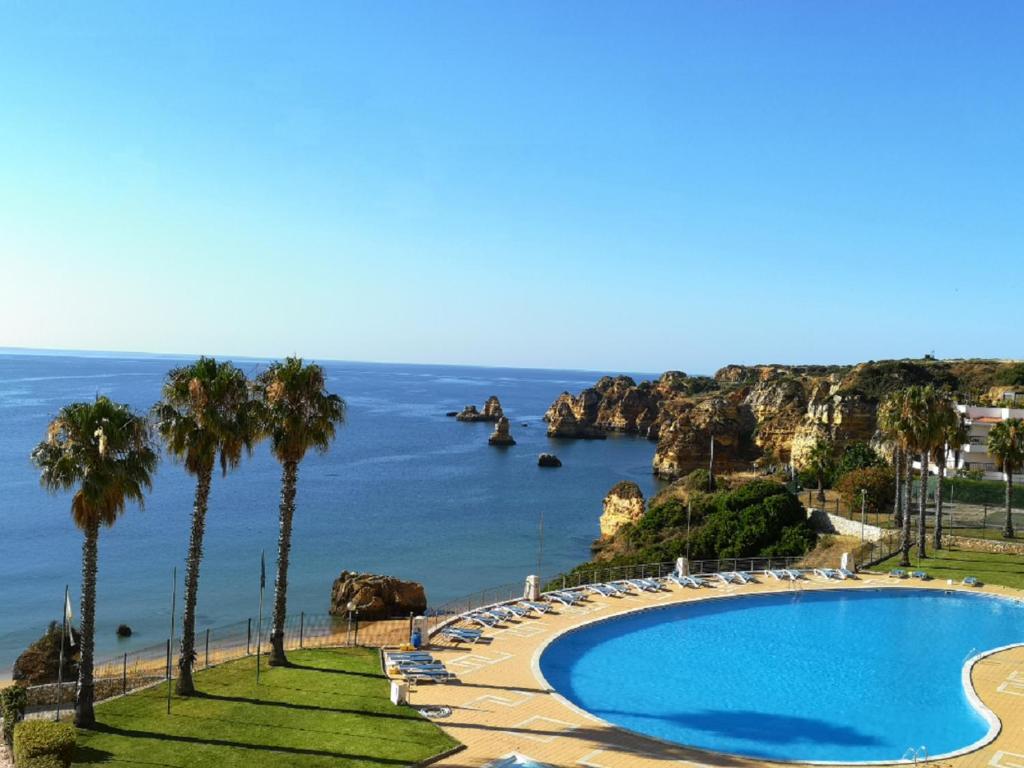 a swimming pool with palm trees and the ocean at WOW OCEAN VIEW, 150mts to Beach & 10 min to Centre in Lagos