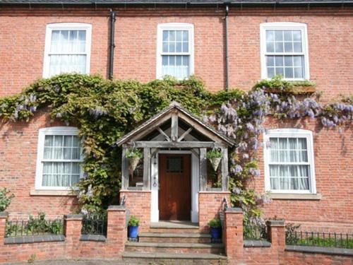 uma casa de tijolos com uma porta e flores nela em Mallories Formerly Kirkby House em Kirkby Mallory