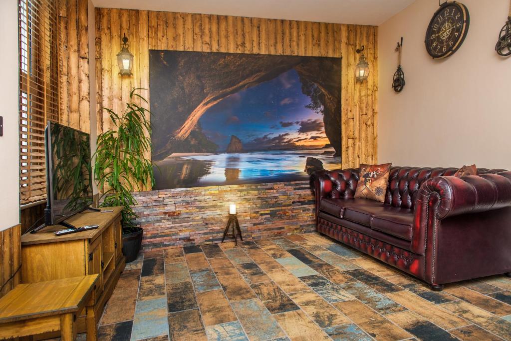 a living room with a leather couch and a painting at Deluxe Pirate's Cove Themed Apartment in St Austell