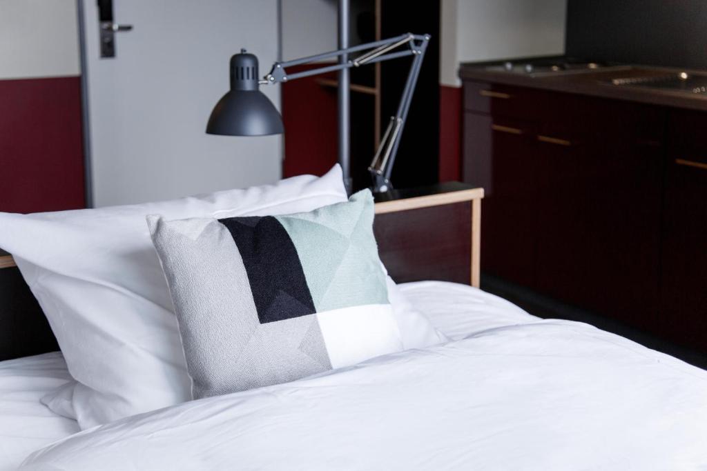 a bed with a black and white pillow and a lamp at Base Apartments in Hamburg