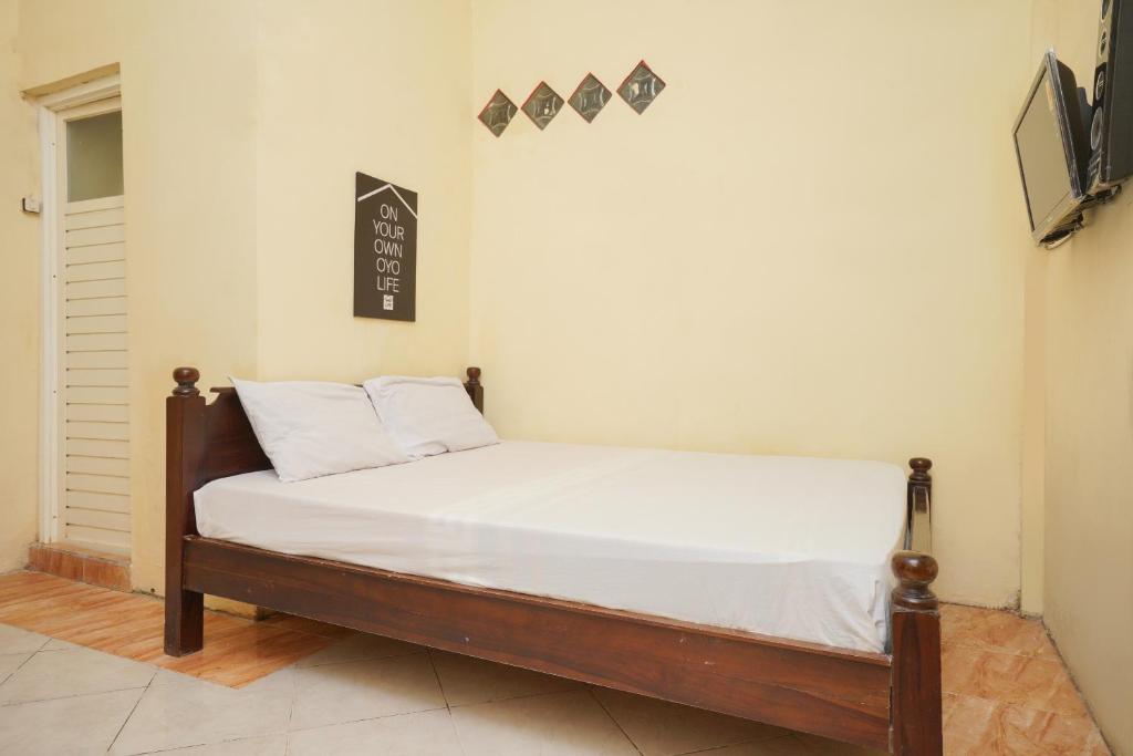a bed in a room with white sheets and pillows at KoolKost Syariah near T1 Juanda Airport 3 in Sidoarjo