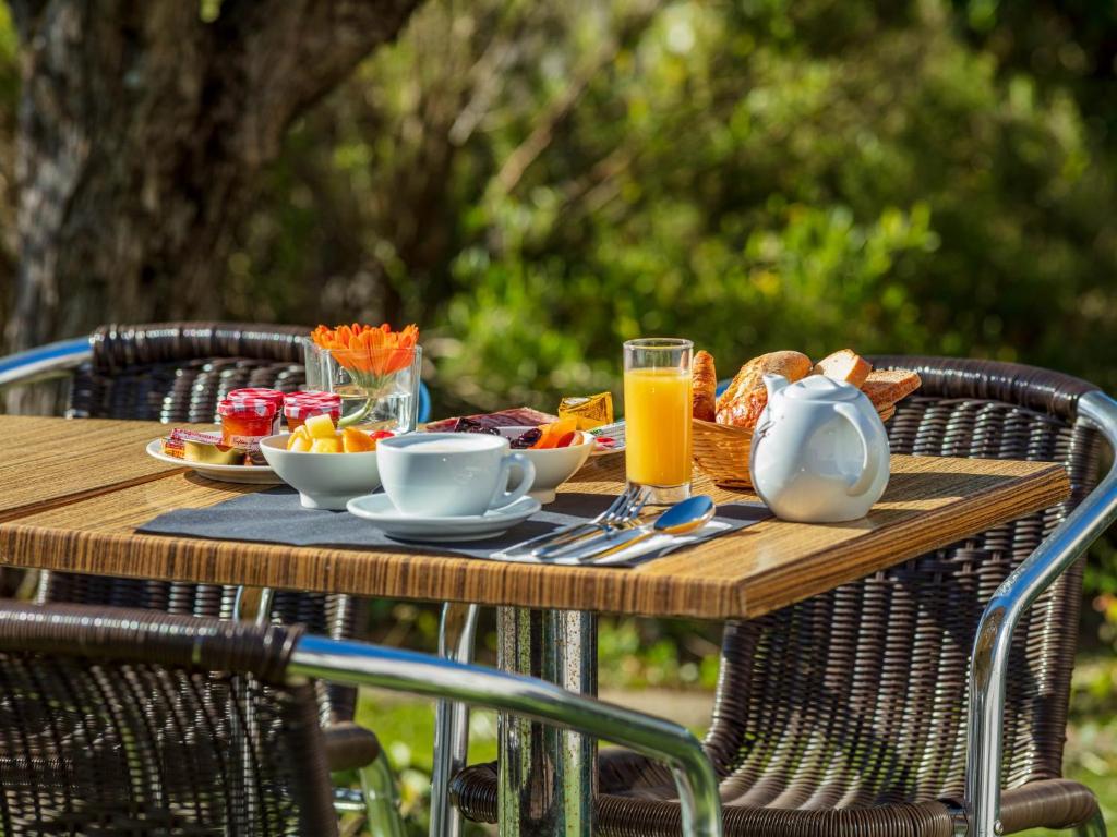 een houten tafel met ontbijtproducten en drankjes erop bij Noemys Valence Nord - hotel restaurant in Bourg-lès-Valence