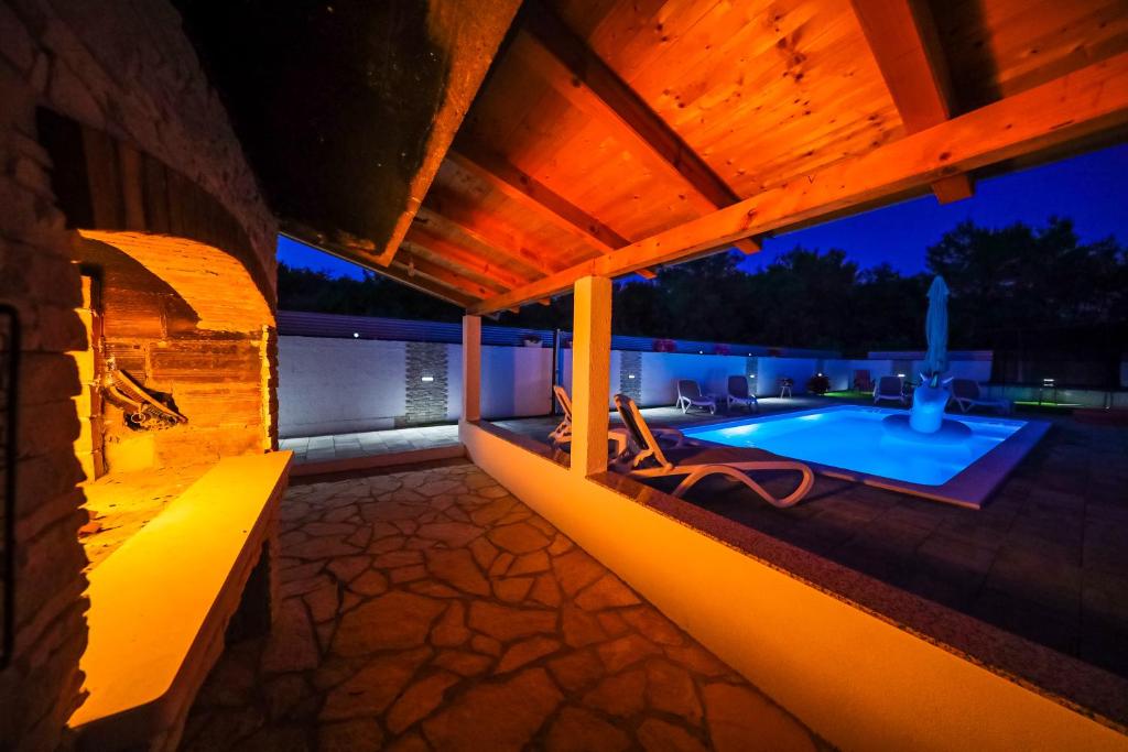 eine Terrasse mit Pool in der Nacht in der Unterkunft Apartment ANAI, Private heated pool and jacuzzi in Sukošan
