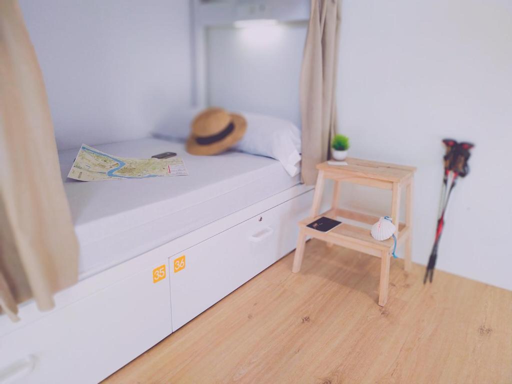 a bedroom with a bed with a hat and a table at Albergue Nacama Hostel Pontevedra PEREGRINOS PILGRIMS in Pontevedra